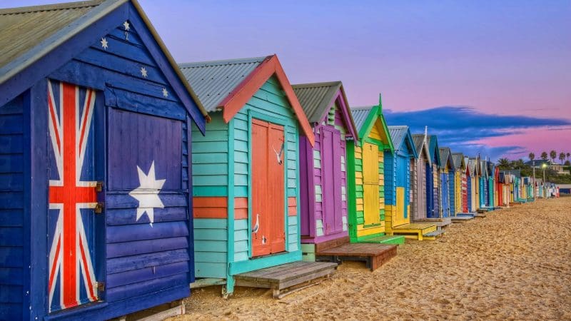 Vibrant beach huts on golden sands beneath a pink sunset highlight Phillip Island Penguin Parade Day Tour’s scenic coastal charm.