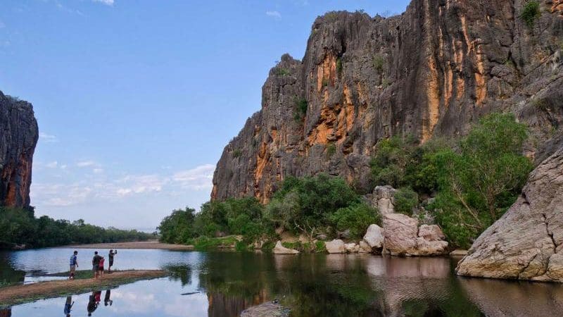 Four travellers by scenic cliffs and tranquil river in Australia—experience the ultimate Darwin to Perth tour package with Broome stays.