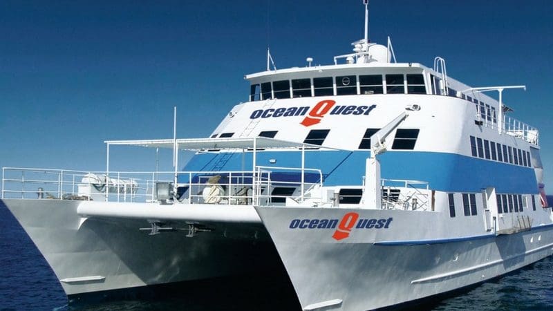 Ocean Quest, a striking white and blue catamaran, floats on serene ocean waters during a 6-Day PADI Open Water diving course.