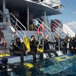 Scuba divers equipped with full kit and fins get ready to dive into the sea during a 4 Day 1 Night Rescue Course (Res1N).