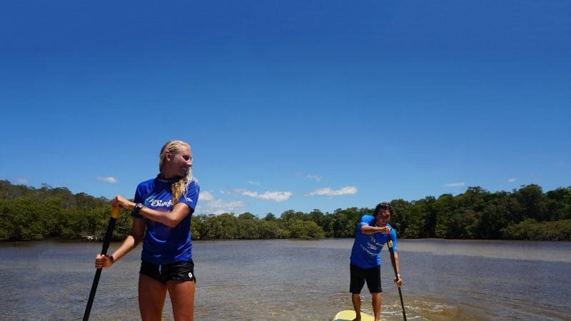 Two people paddleboarding on tranquil waters during the Byron Bay Group 2 five-hour stand up paddle board tour experience.