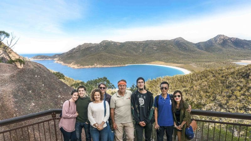 Tourists gather at a panoramic lookout, enjoying stunning views of Wineglass Bay and lush mountains on the Richmond full-day tour.