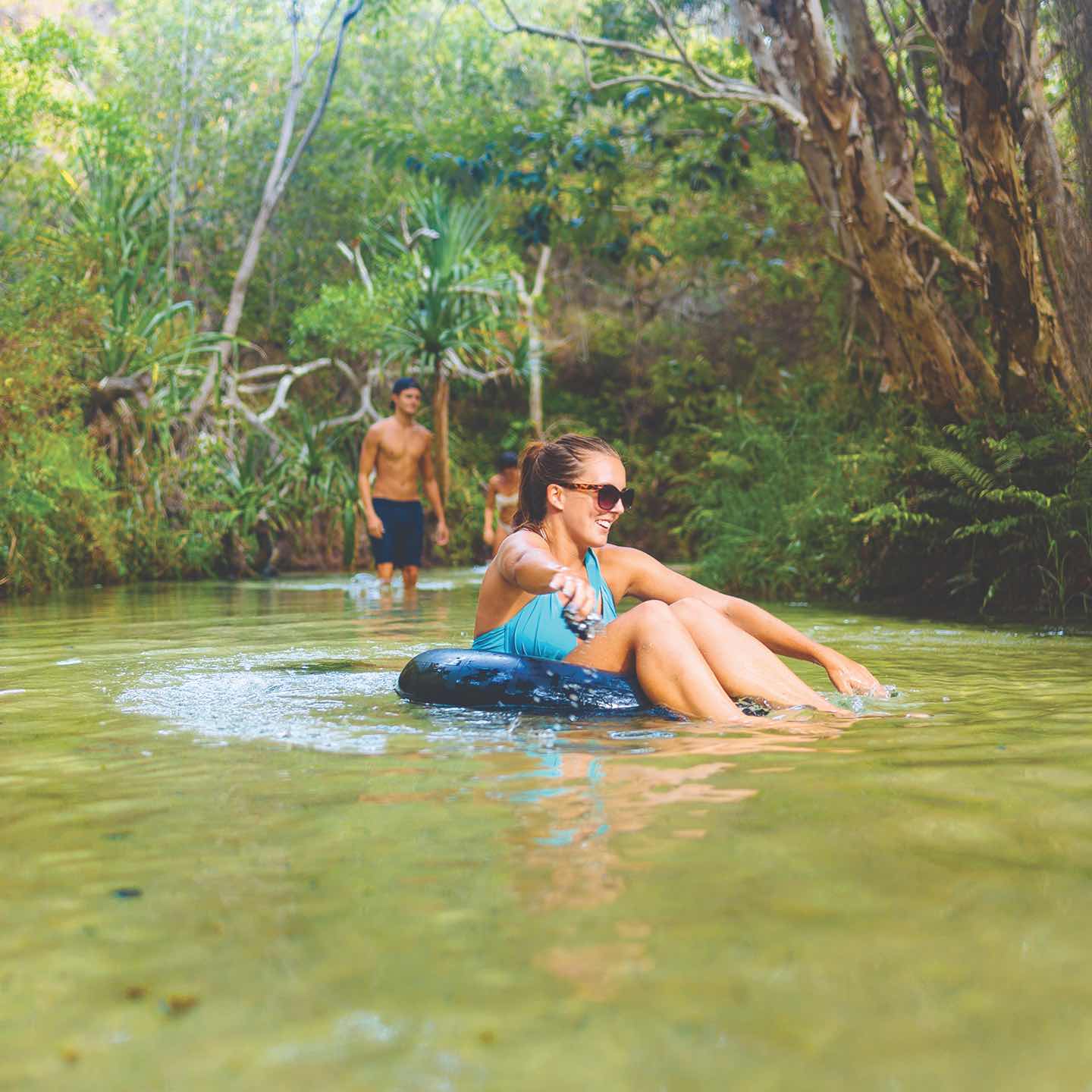 Adventurous woman in blue swimming costume tubing on crystal-clear creek during 2 Day K'gari Fraser Island Tag Along Adventure with Dingos tour.