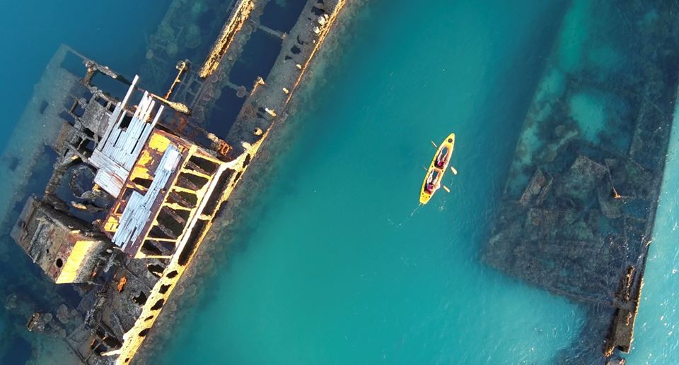 Aerial view of a yellow kayak with two people touring the stunning Moreton Island Wrecks in crystal-clear blue water Adventure.