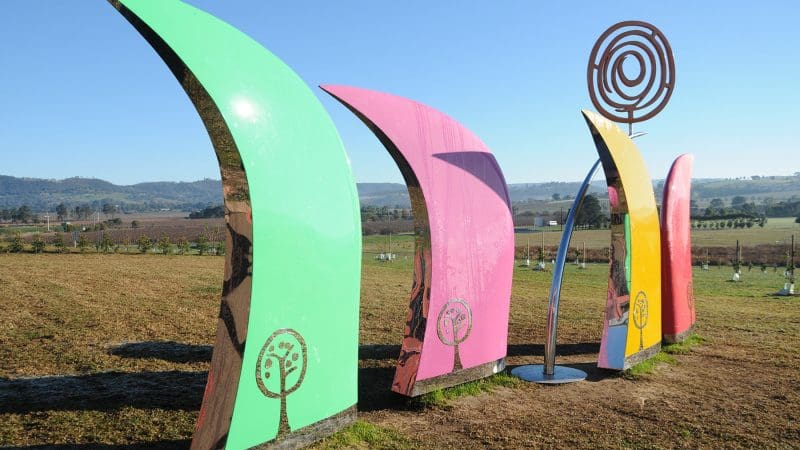 Vibrant abstract outdoor sculptures resembling curved fins, displayed along the scenic 1 Day Lake Mountain Snow Waterfalls Tour route.