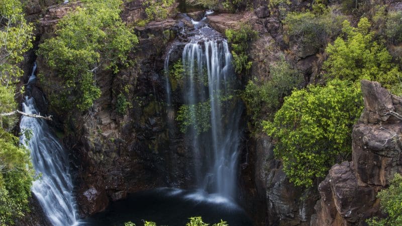 Litchfield National Park waterfall flowing over rugged rocks, lush greenery, ideal scenic spot for top-rated 1 Day Crocodile Cruise.