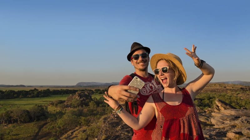 Happy couple in sun hats and sunglasses taking a selfie during their Kakadu Wilderness Escape at Fogg Dam Wetlands, Australia.