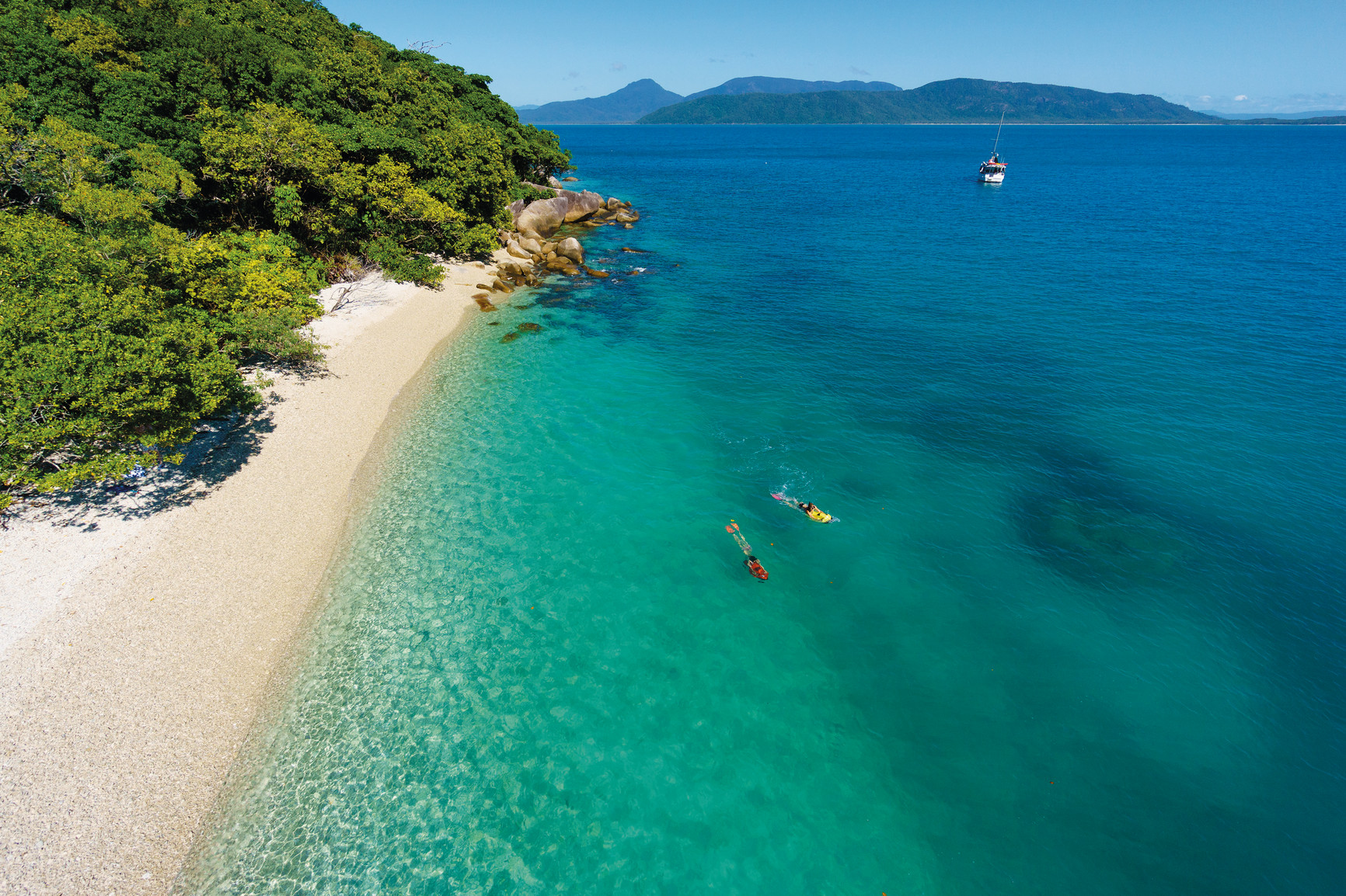Stunning aerial shot of snorkellers exploring crystal-clear blue waters on a Fitzroy Island Ferries full-day tour near Fitzroy Island.