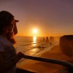 Traveller experiences the iconic Great Ocean Road Sunset Tour, viewing the sun set over dramatic coastal cliffs and breathtaking seascapes.