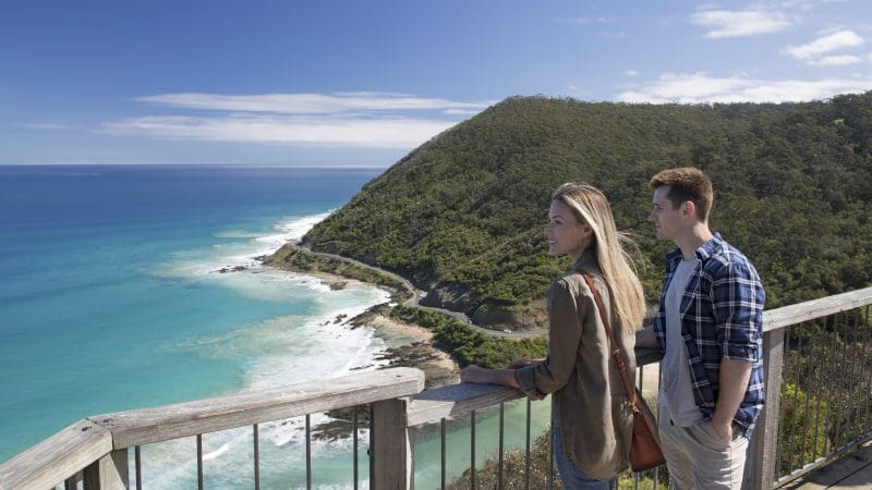 Two travellers admire scenic coastal views from a wooden lookout on a 2 Day Great Ocean Road Grampians Escape starting in Melbourne.