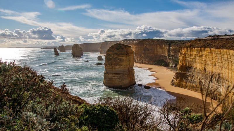 Majestic rock formations emerge from the ocean along the stunning, sandy coastline of the 1 Day Great Ocean Road Reverse Eco Tour.