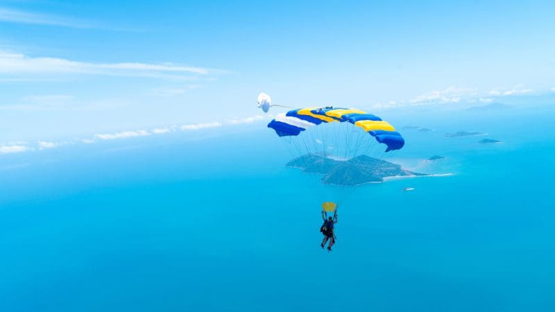 Tandem skydiver at Mission Beach plunges from 15,000ft above crystal blue ocean, islands, and clear sunny skies in Australia.