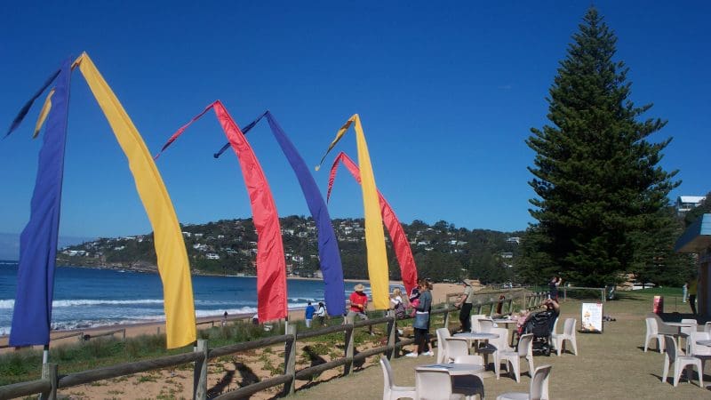 Vibrant flags flutter near a picturesque beachside lounge, ideal for Celebtime Tours' top-rated 1 Day Home Away getaway experience.