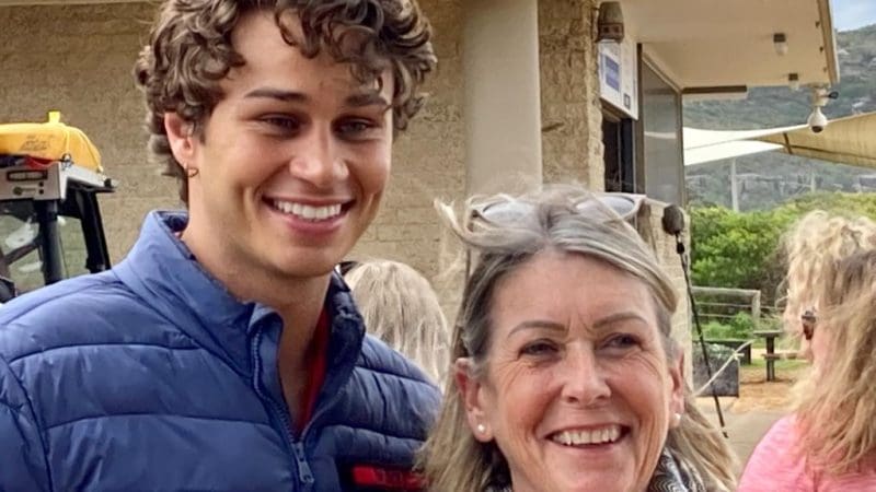 Young man in blue jacket smiling outside with older woman during Celebtime Tours 1 Day Home Away Tour, enjoying sightseeing.