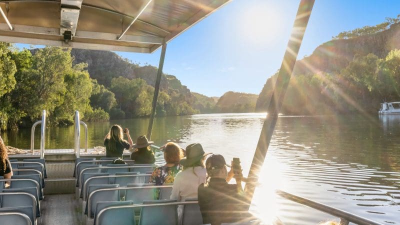 Travellers on a 1 Day Katherine Gorge Cruise savour panoramic river vistas, verdant hills, and sparkling sunlight dancing on the water.