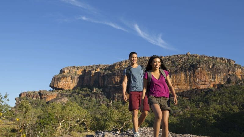 Two adventurers hike a rocky trail during the 5 Day Kakadu, Katherine Gorge, and Litchfield 4WD Adventure Tour from Darwin.