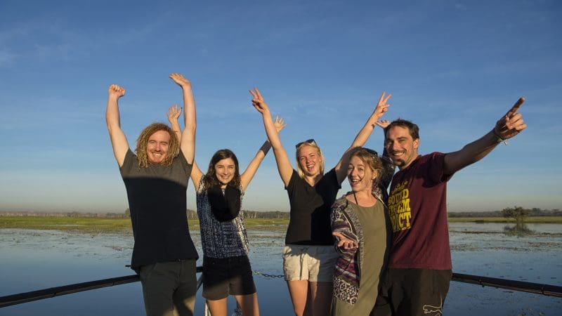 Group of five people celebrating on a boat, taking in Kakadu and Litchfield National Park’s stunning landscapes on a 3-day 4WD safari tour.