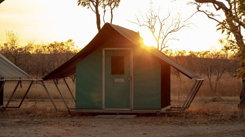 Green tent cabin glowing at sunset, ideal lodging for a 3-Day Kakadu Litchfield National Park 4WD Safari Tour adventure.