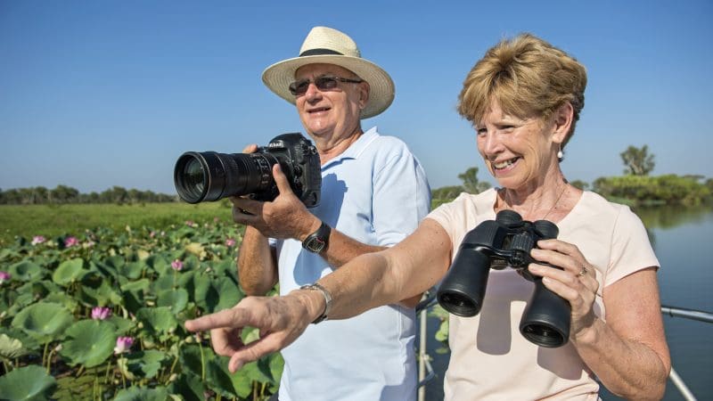 Happy senior couple enjoying birdwatching by lily pads on a Half Day Jumping Crocodile Tour from Darwin, Northern Territory.