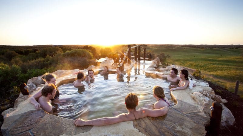 Group unwinds in a scenic hot spring at sunset, savouring the Peninsula Hot Springs Spa Entry & Shuttle Bus 1-Day Experience.