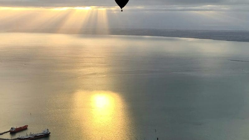 Hot air balloon at sunrise over The Great Ocean Flight Geelong and Bellarine, calm waters, ships below, breakfast included.