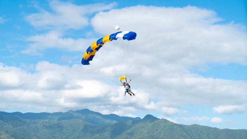 Experience the thrill of a Wollongong 15,000ft tandem skydive above lush green mountains and scenic clouds for an unforgettable adventure.