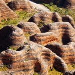 Vibrant striped sandstone domes with lush green crevices in sunlight on a 10 Day Darwin to Broome 4WD Adventure tour, Australia.