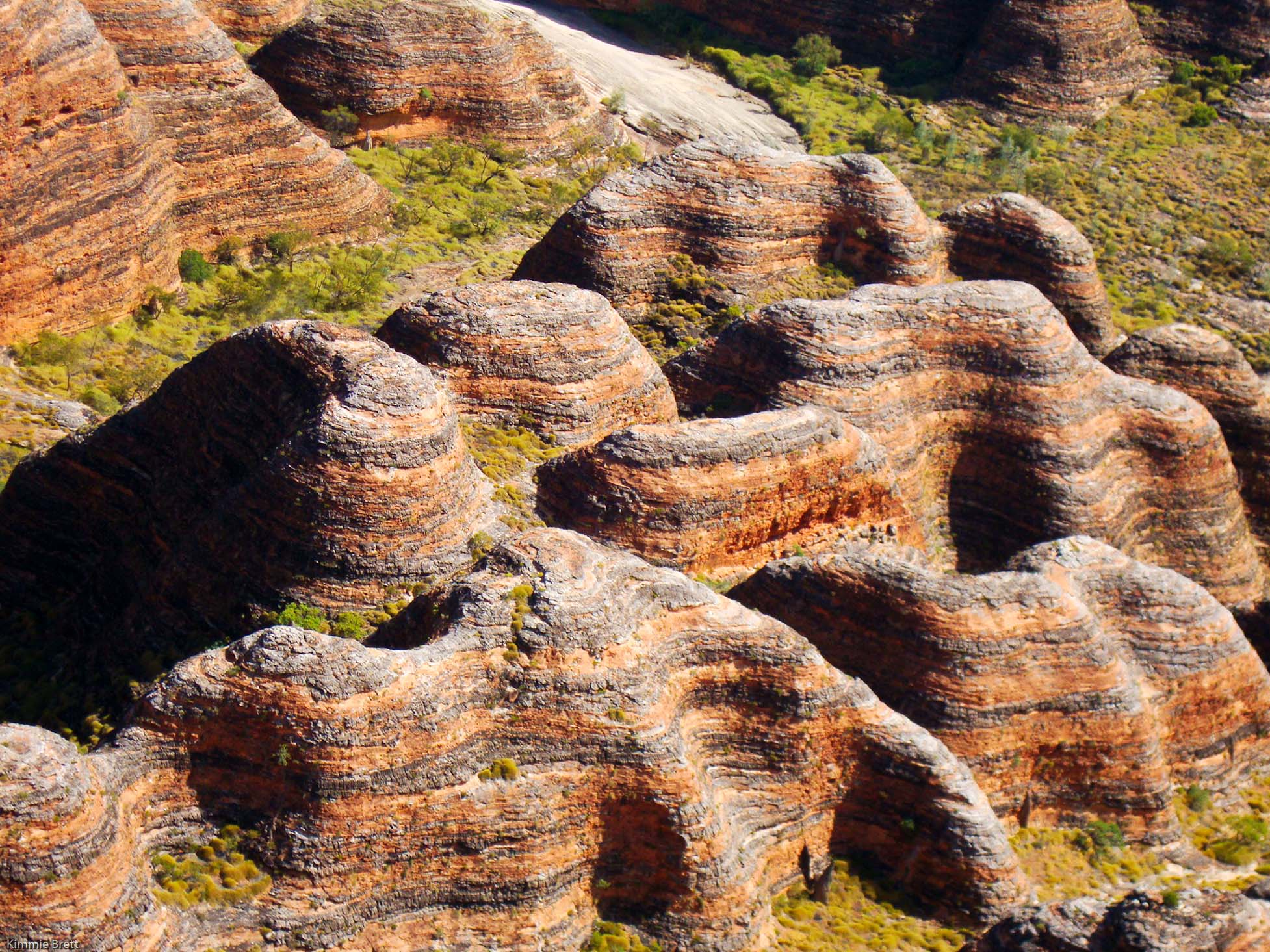 Vibrant striped sandstone domes with lush green crevices in sunlight on a 10 Day Darwin to Broome 4WD Adventure tour, Australia.