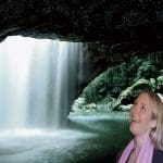 Smiling couple pose by a stunning cave waterfall during a popular Natural Bridge Glow Worm Night Tour from the Gold Coast, Australia.