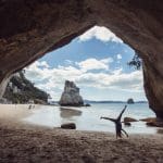Image of a Joyful person doing a cartwheel on a beach in New Zealand during their Kiwi Experience on the Jandal Classic tour
