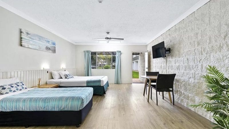 Spacious hotel room with double and single beds, flat-screen TV, work table, and large window—ideal stay before Kgari 2 Day Tour.