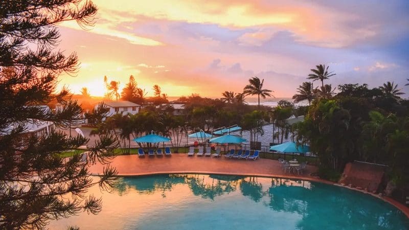 Luxury swimming pool with loungers and parasols at sunset, ideal for relaxing after a Kgari 2 Day Tour Ex Hervey Bay experience.