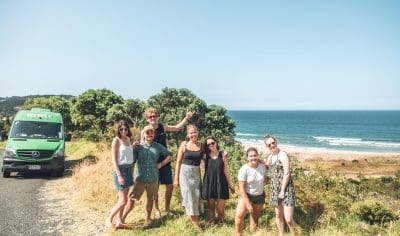 Smiling group of friends posing for a photo during their Grand Kiwi Experience adventure in New Zealand’s stunning outdoors.