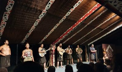 Diverse group of talented performers engaging the audience on a brightly lit stage during a live theatrical or musical performance.