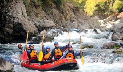Adventurous group of people white-water rafting together, paddling through rapids on a scenic river, enjoying teamwork and excitement.