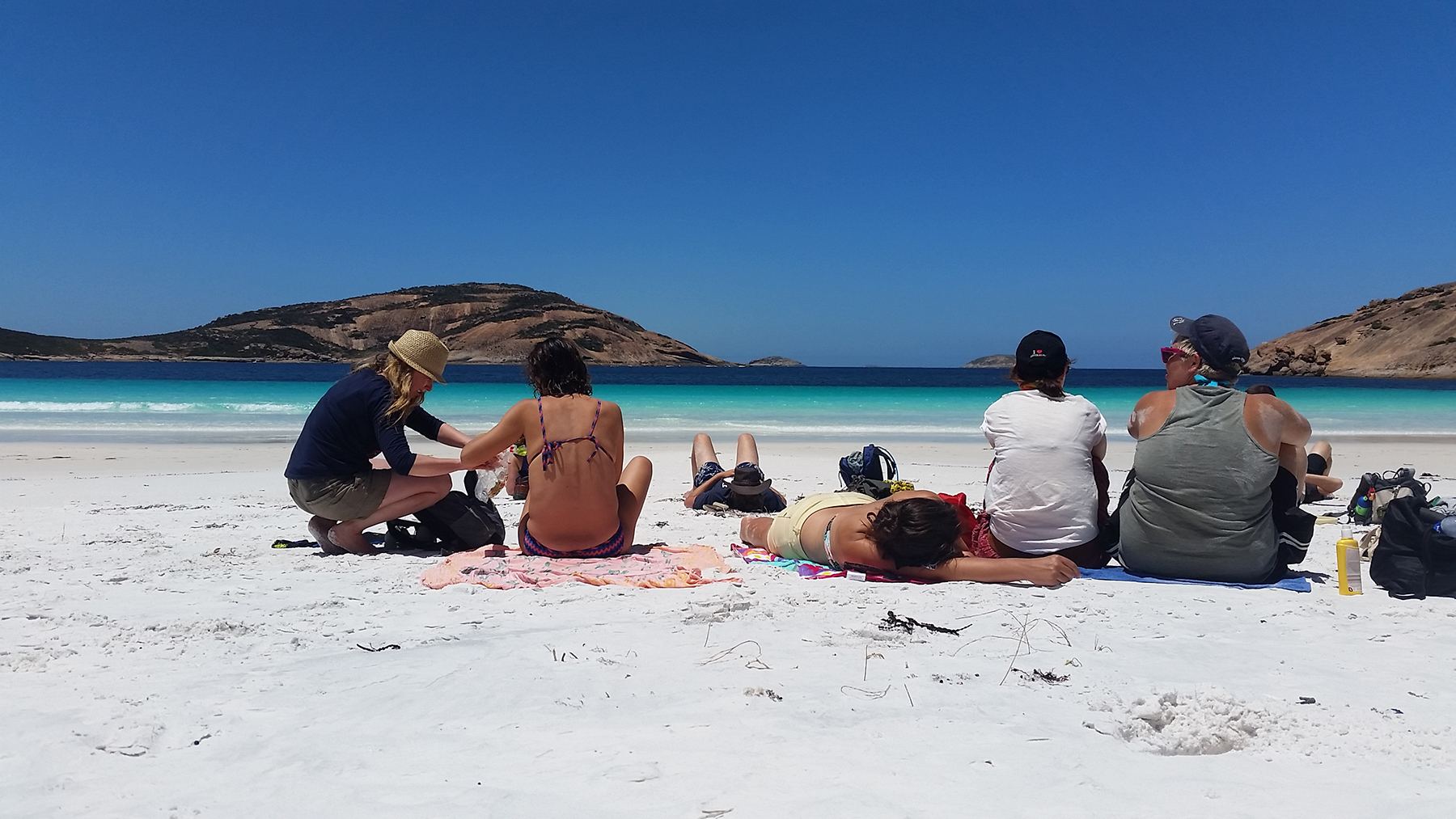 Six travellers relax on pristine white sand at Esperance Beach, part of Untamed Escapes’ 6 Day Margaret River Adventure Tour in Australia.
