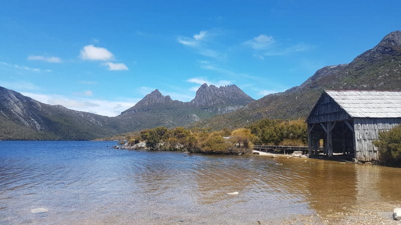 Stunning view of Cradle Mountain, serene lake, and historic wooden boathouse on the 4 Day Wild Tasmania Wilderness Loop tour.