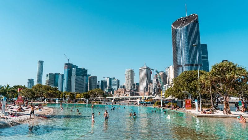 Travellers enjoy swimming and sunbathing at a vibrant city beach on the top-rated Fully Guided Ultimate East Coast Melbourne to Cairns tour.