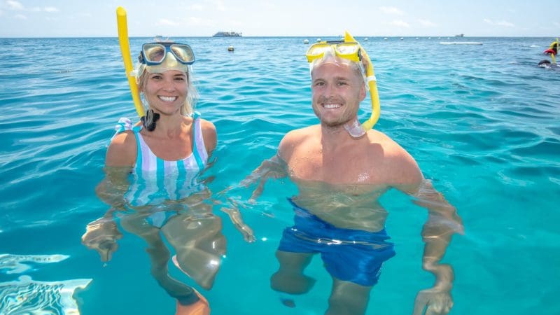 Two snorkellers smile brightly under the sun at the iconic Great Barrier Reef Activity Platform, ready for an unforgettable adventure.