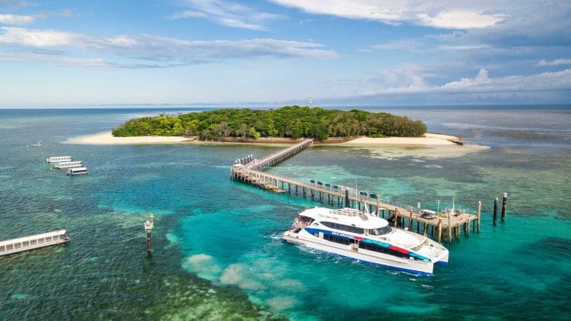 White boat at Green Island pier over crystal-clear turquoise water, ideal for snorkelling or glass-bottom boat tours in Australia.
