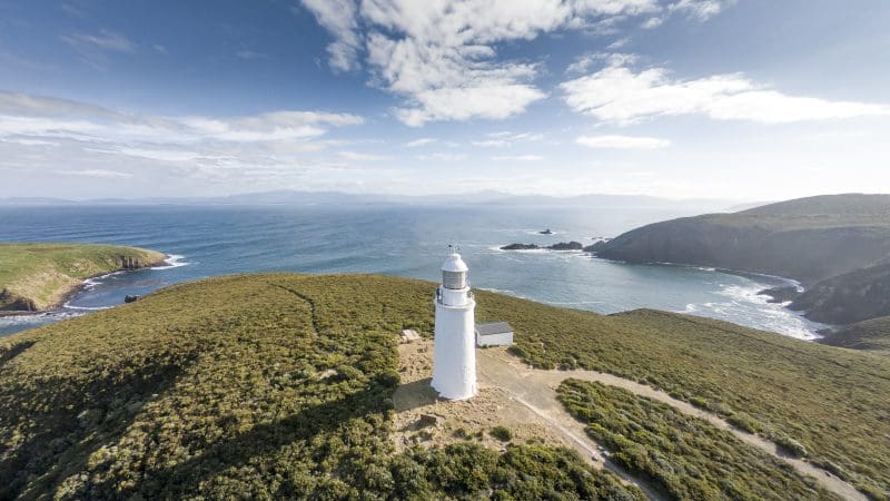 Iconic white lighthouse set on lush green Bruny Island coast, featured in Cape Bruny Lighthouse and Food Sightseeing Tours, Tasmania.