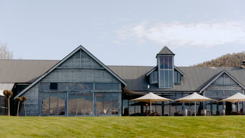 Modern rustic venue with expansive windows, outdoor patio seating, and shaded parasols—perfect for Coal River Valley Wine & Gin Safaris tours.