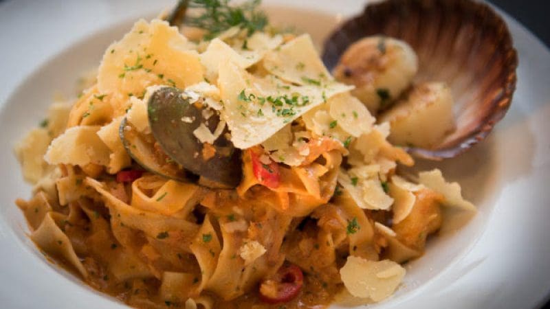 Delicious tagliatelle pasta in rich creamy sauce, topped with fresh clams and parmesan at Sorrentos—ideal pre-cruise dining.
