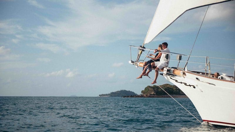 people sitting infront of sailing boat with ocean view