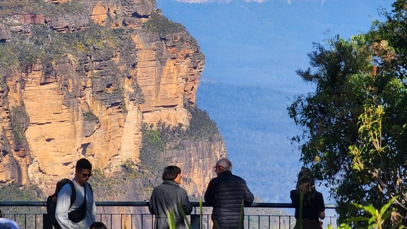 Group of four at panoramic Blue Mountains lookout on guided day tour with waterfall walk and social lunch, stunning scenic views.