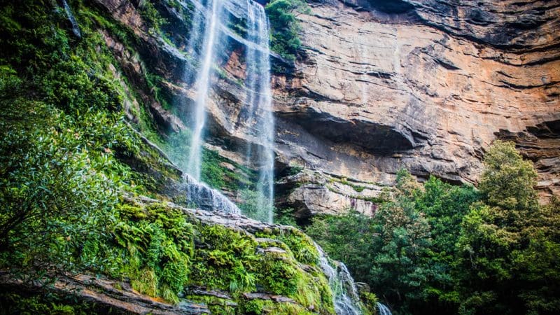 Majestic waterfall plunges beside rugged cliffs, conveniently accessible via Explorer Bus Pass Hop-On Hop-Off sightseeing service.