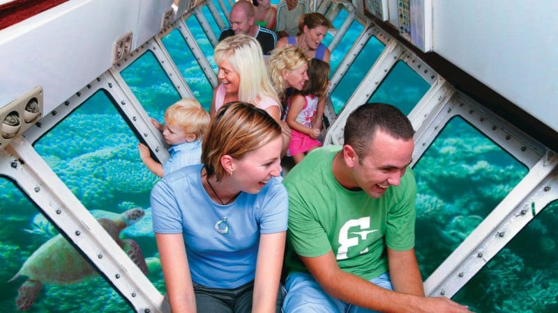 Tourists inside a submarine view vibrant sea turtles through large windows on the Half-Day Green Island 9AM Departure tour.