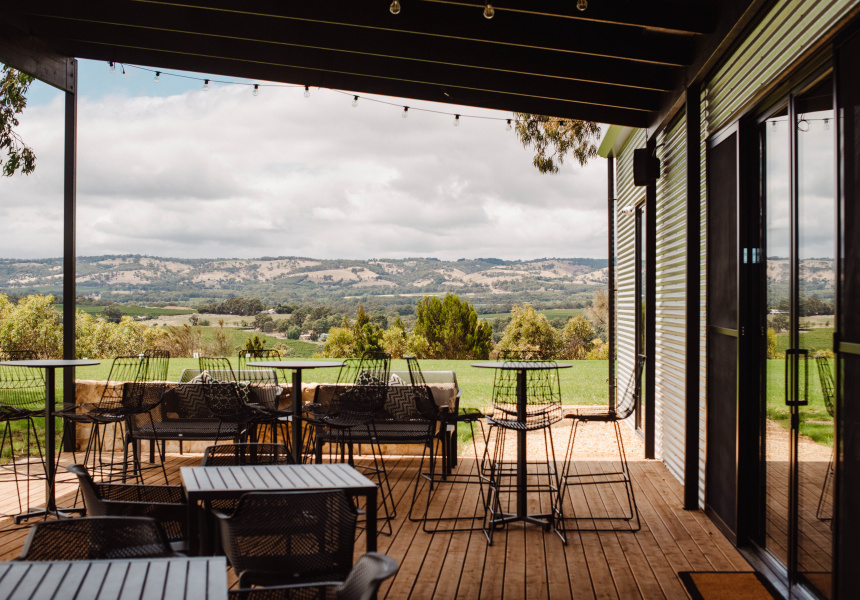 Experience stunning views of McLaren Vale South from an outdoor patio with sleek black metal tables, chairs, and Hop On Hop Off Tour allure.