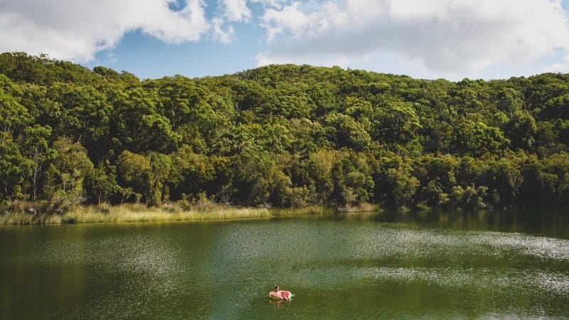 Discover ultimate relaxation as a traveller lounges on a pink float in a serene green lake during the calming Kgari 4 Day Experience.