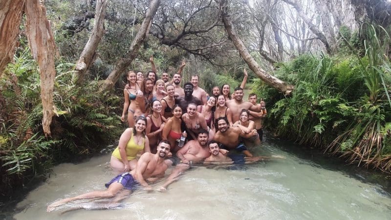Happy group in swimwear poses in a scenic creek during a Kgari Safari Tour on Fraser Island, enjoying an unforgettable Australian adventure.